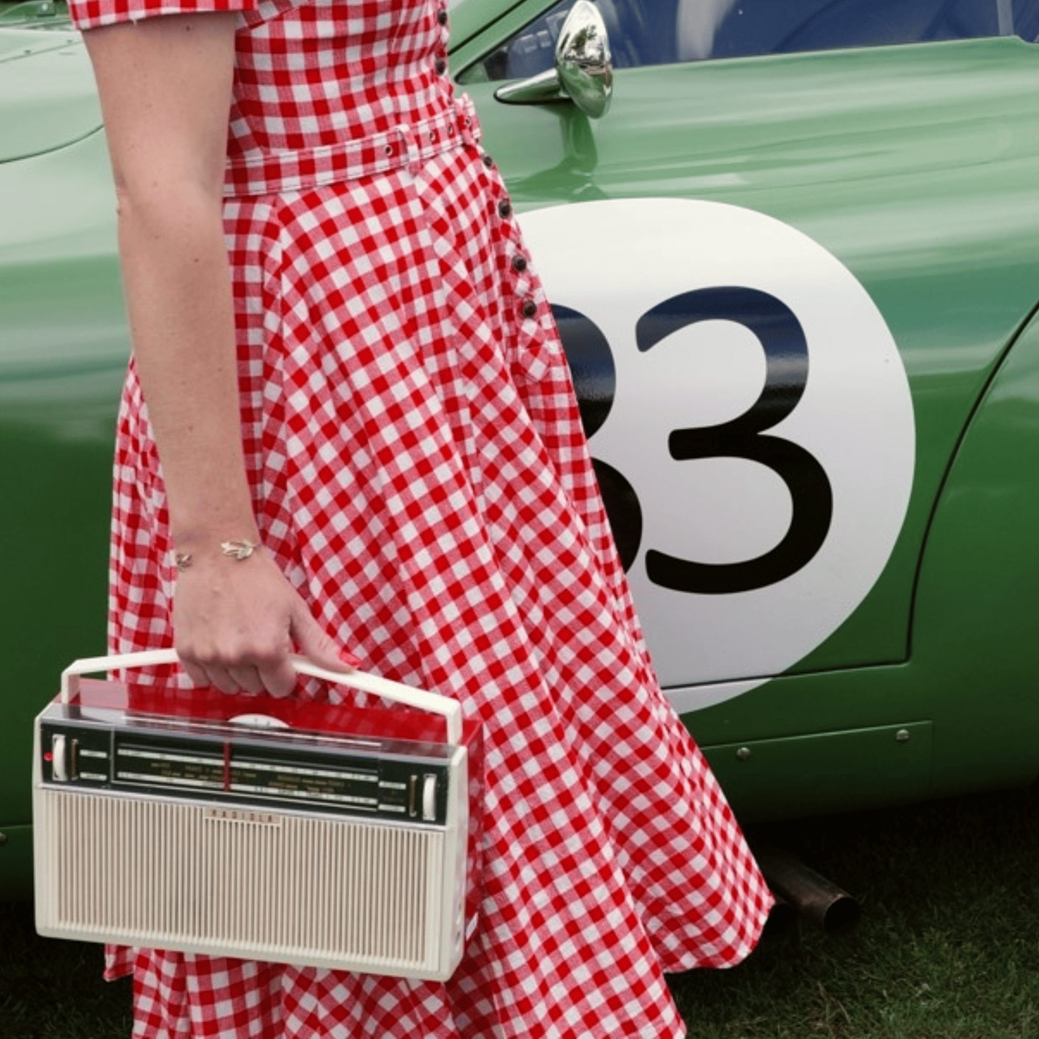 Femme portant une radio vintage modernisรฉe devant une voiture de collection