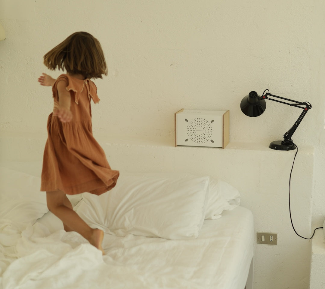 Enceinte Bluetooth Haute fidélité PRODIGE posée au dessus d'un lit avec une enfant entrain de danser